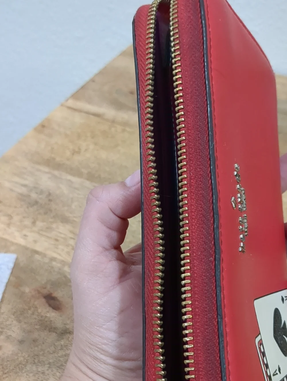 Kate Spade red zip-around wallet with Ace of Spades patch